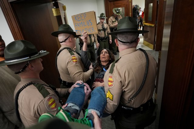 Ashley Warbington, holding a sign that says “keep families together”, is carried out of a House committee meeting by state troopers in Nashville, Tennessee, on Wednesday, January 29, 2025. At least three woman were ejected from the meeting on immigration, according to the Associated Press. (Photo by George Walker IV/AP Photo)