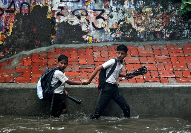 School children wade through a waterlogged street after heavy rains in Mumbai, India July 3, 2018. (Photo by Francis Mascarenhas/Reuters)