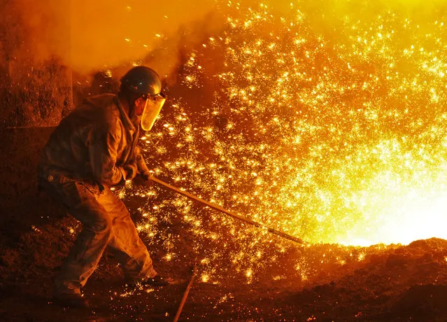 An employee works next to molten iron at a steel mill of Dongbei Special Steel in Dalian, Liaoning province, China July 17, 2018. (Photo by Reuters/China Stringer Network)