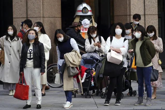 People wearing protective masks to help curb the spread of the coronavirus wait for a traffic light at an intersection Monday, March 1, 2021, in Tokyo. The Japanese capital confirmed more than 120 new coronavirus cases on Monday. (Photo by Eugene Hoshiko/AP Photo)