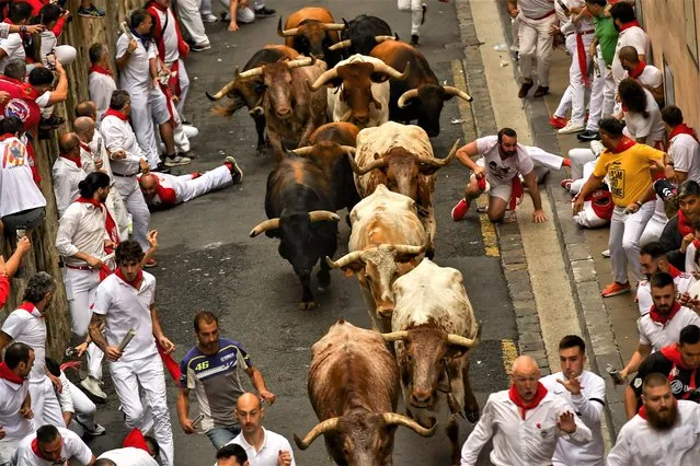 La Palmosilla's fighting bulls run among revellers during the first day of the running of the bulls during the San Fermin fiestas in Pamplona, Spain, Friday, July 7, 2023. (Photo by Alvaro Barrientos/AP Photo)