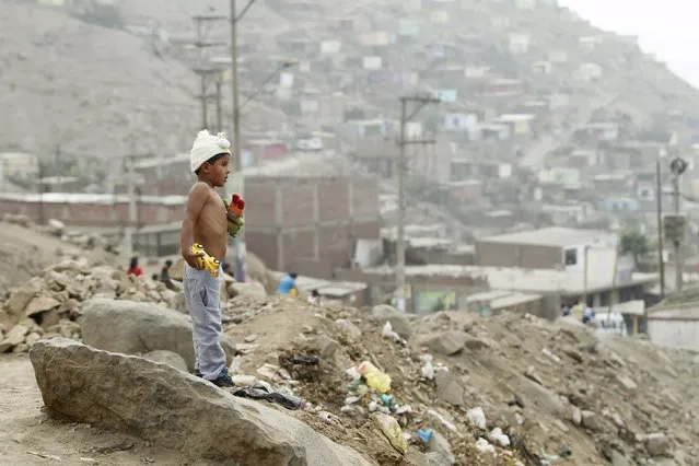 A boy stands with his toys during Christmas celebration in Huaycan on the outskirts of Lima, Peru December 15, 2015. (Photo by Janine Costa/Reuters)