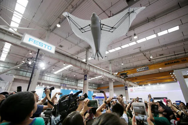 Visitors take pictures of a bionic flying fox at Festo's booth at the WRC in Beijing, China on August 15, 2018. (Photo by Jason Lee/Reuters)