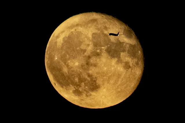 A jetliner flying from JFK is silhouetted against the moon, Wednesday, August 2, 2023, in New York. (Photo by Bebeto Matthews/AP Photo)