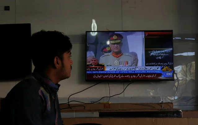 A salesman watches incoming Army Chief of Staff Lieutenant General Qamar Javed Bajwa during the handover ceremony broadcasted on a television while waiting for customers at an electronics shop in Karachi, Pakistan November 29, 2016. (Photo by Akhtar Soomro/Reuters)