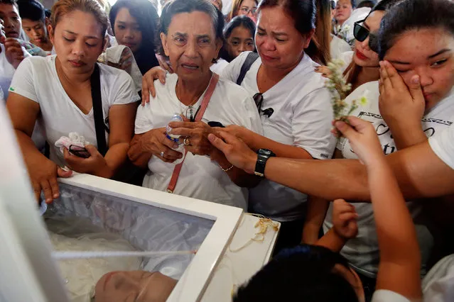 The mother, wife, and other relatives of Florjohn Cruz, who was killed in a police drugs buy-bust operation, mourn by his coffin during his funeral in Manila, Philippines October 30, 2016. (Photo by Damir Sagolj/Reuters)