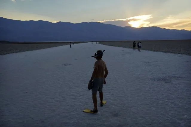 Marko Leszczuk walks along the salt flats at Badwater Basin as the sun sets, Sunday, July 16, 2023, in Death Valley National Park, Calif. Leszczuk, who was recently snorkeling and had his gear in his truck, decided to jokingly wear them out. Death Valley's brutal temperatures come amid a blistering stretch of hot weather that has put roughly one-third of Americans under some type of heat advisory, watch or warning. (Photo by John Locher/AP Photo)