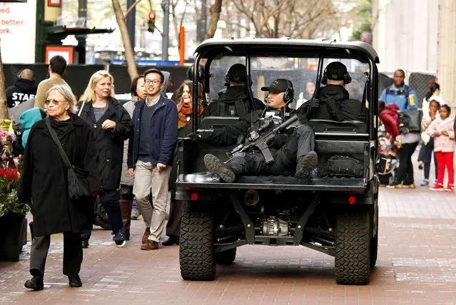 A San Francisco police officer rides in the back of a cart on Market Street outside Super Bowl City, a pro-football's weeklong theme park near the famed Ferry Building on The Embarcadero in San Francisco on Wednesday, February 3, 2016. Super Bowl City is a free-to-the-public fan village to celebrate Super Bowl 50. (Photo by Eric Risberg/AP Photo)