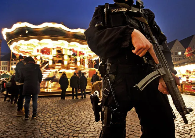 A German police officer stands near a merry-go-round guarding the Christmas market in Frankfurt, Germany, Monday, December 17, 2018. (Photo by Michael Probst/AP Photo)
