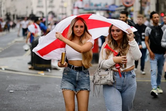 England fans shelter from the rain under flags ahead of the UEFA EURO 2020 final football match between England and Italy in central London on July 11, 2021. (Photo by Tolga Akmen/AFP Photo)