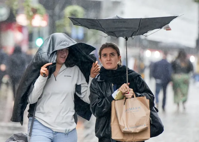 Members of the public brave the rain and the strong winds in Manchester City centre on October 13, 2023. A yellow weather warning for rain is in place for parts of the UK. (Photo by Ioannis Alexopoulos/London News Pictures)
