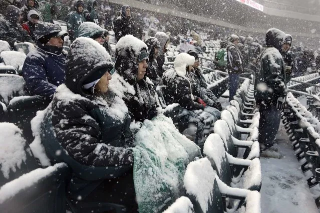 Fans covered with snow wait in the stands before a game between the Philadelphia Eagles and the Detroit Lions in Philadelphia, on December 8, 2013. (Photo by Matt Rourke/Associated Press)