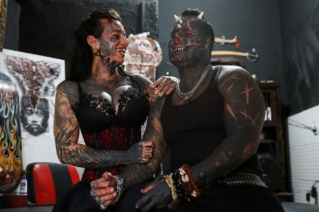 Brazilian tattoo artist Michel Praddo, also known as Diabao or Human Satan, and his wife Carol Praddo, known as Mulher Demonia or Demon Woman, laugh as they talk about body modifications in their studio in Praia Grande, Brazil on August 18, 2021. (Photo by Carla Carniel/Reuters)