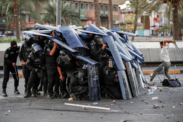 Iraqi riot-control police take cover behind their shields during clashes with protesters gathering on the 4th anniversary of the 2019 Iraqi anti-government demonstrations in Baghdad's Tahrir square on October 1, 2023. (Photo by Ahmad Al-rubaye/AFP Photo)