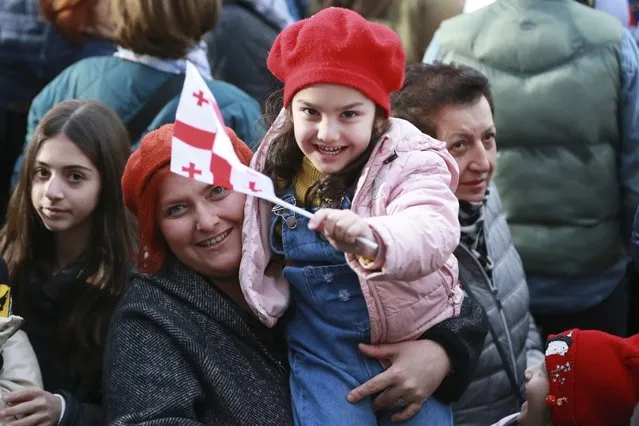 A woman holds her child waving a national flag as they celebrate Georgia's EU candidacy at Liberty Square in Tbilisi, Georgia, on Friday, December 15, 2023. Several thousand people attend a march in support of Georgia's EU candidacy. European Union flags waved across Georgia Friday after the European Council took a step forward along the long road towards granting Georgia and Moldova as EU membership. (Photo by Zurab Tsertsadze/AP Photo)