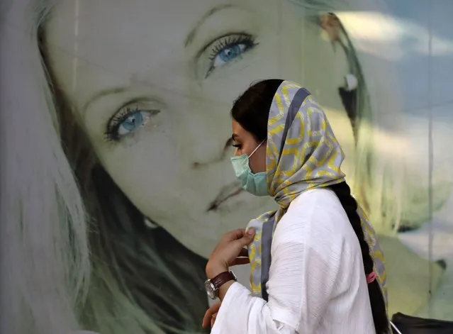 A woman wearing protective face mask to help prevent the spread of the coronavirus walks past an advertisement of skin care products in southern Tehran, Iran, Tuesday, July 20, 2021. Iran on Tuesday broke another record in the country's daily new coronavirus cases, even as Tehran and its surroundings went into lockdown, a week-long measure imposed amid another surge in the pandemic. (Photo by Vahid Salemi/AP Photo)