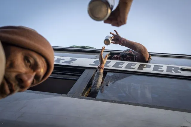 Indian pilgrims deliver tea to their family members through the window of a bus before they embark on a visit to the sacred Pashupatinath temple in Kathmandu, Nepal, January 9, 2024. (Photo by Niranjan Shrestha/AP Photo)