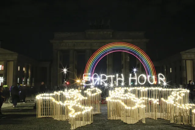 Activists of the World Wide Fund For Nature (WWF) write the words 'Earth Hour' with led-lights in front of the blacked out Brandenburg Gate to mark Earth Hour, in Berlin, Saturday, March 30, 2019. The global event Earth Hour is the symbolic switching off of the lights for one hour to help minimalize fossil fuel consumption as well as mitigate the effects of climate change. (Photo by Markus Schreiber/AP Photo)