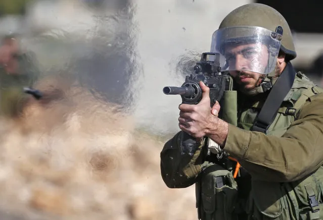 An Israeli soldier fires a rubber bullet towards Palestinian protestors during clashes following a weekly demonstration against the expropriation of Palestinian land by Israel in the village of Kfar Qaddum, near Nablus, in the occupied West Bank on February 10, 2017. (Photo by Jaafar Ashtiyeh/AFP Photo)