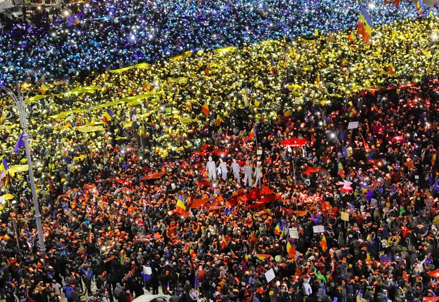 People light the flashes of their mobile phones in the colors of Romania's flag during an anti-government protest in Bucharest, Romania, Sunday, February 12, 2017. Protesters braved freezing temperatures gathering outside the government headquarters for the 13th consecutive day to demand the government's resignation after it passed a decree that would have diluted the anti-corruption fight that has targeted top officials. (Photo by Vadim Ghirda/AP Photo)