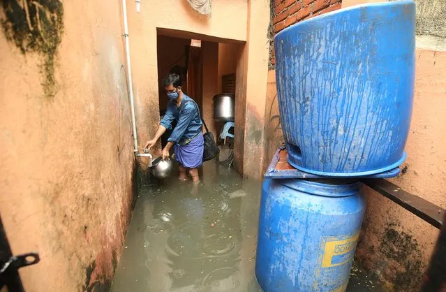 A man collects drinking water from a tap inside his flooded house after heavy rainfall in Chennai, India, November 8, 2021. (Photo by P. Ravikumar/Reuters)