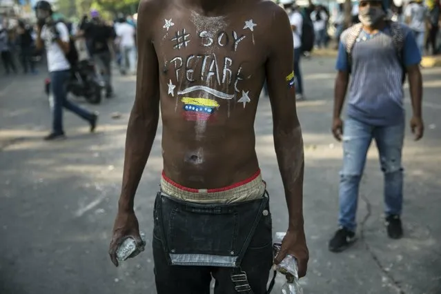 Anti-government protester Albert Gonzales holds rocks to throw at the National Police during clashes near La Carlota airbase in Caracas, Venezuela, Wednesday, May 1, 2019. (Photo by Rodrigo Abd/AP Photo)