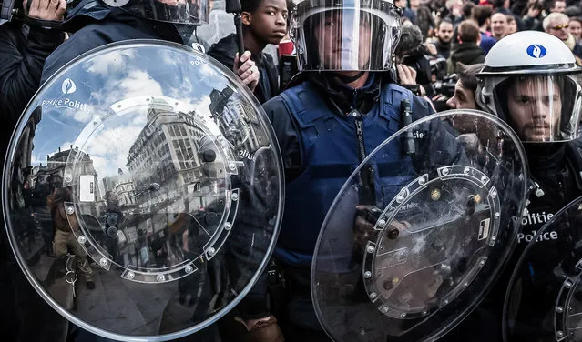 Riot police attend a memorial site during a protest by right wing demonstrators at the Place de la Bourse in Brussels, Sunday, March 27, 2016. In a sign of the tensions in the Belgian capital and the way security services are stretched across the country, Belgium's interior minister appealed to residents not to march Sunday in Brussels in solidarity with the victims. (Photo by Valentin Bianchi/AP Photo)