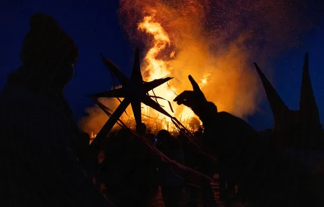 Revellers watch the burning installation called "Black Mount" during the celebrations of Maslenitsa, a pagan holiday marking the end of the winter, in the village of Nikola-Lenivets in Kaluga region, Russia on March 16, 2024. (Photo by Maxim Shemetov/Reuters)