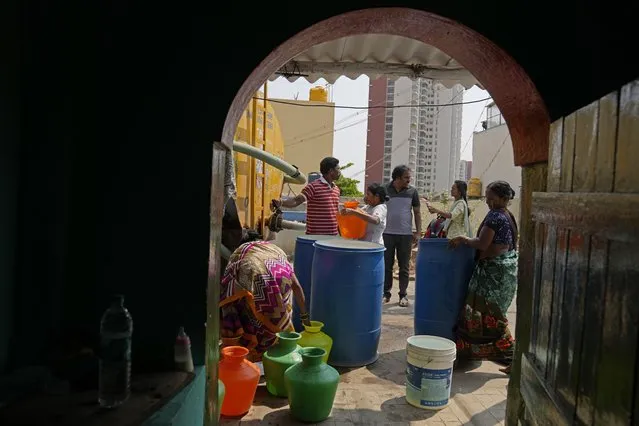 Residents of Ambedkar Nagar, a low-income settlement in the shadows of global software companies in Whitefield neighborhood, collect potable water from a private tanker in Bengaluru, India, Monday, March 11, 2024. (Photo by Aijaz Rahi/AP Photo)