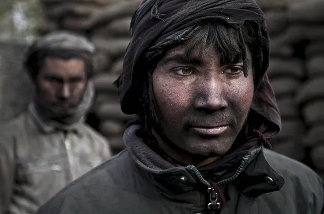 Qudrat, 18, right, poses for a photograph as he works at a charcoal shop on the outskirts of Kabul, Afghanistan, Monday, November 4, 2013. As winter is approaching, wood and charcoal are getting expensive among all other necessities for most Afghans. (Photo by Rahmat Gul/AP Photo)