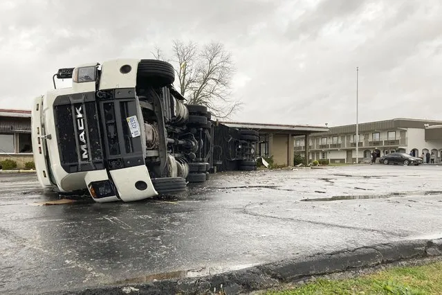 A large semi trailer is flipped over and pushed against a building in Bowling Green, Ky., on Saturday, December 11, 2021. Tornadoes and severe weather caused catastrophic damage across multiple states late Friday, killing at least six people overnight as a storm system tore through a candle factory in Kentucky, an Amazon facility in Illinois and a nursing home in Arkansas. (Photo by Dylan T. Lovan/AP Photo)