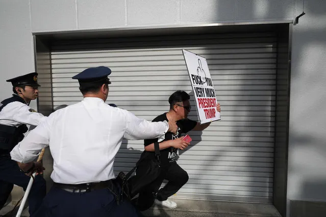 A man holding an anti-Trump slogan runs away as Japanese policemen try to take him away from the street around the Ryogoku Sumo Hall, where US President will visit, in Tokyo on May 26, 2019. (Photo by Behrouz Mehri/AFP Photo)