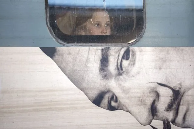 A child looks out from the window of a train displaying an advert to a Salvador Dali exhibition, at Gara de Nord, the main railway station in Bucharest, Romania, Friday, March 29, 2024. (Photo by Andreea Alexandru/AP Photo)