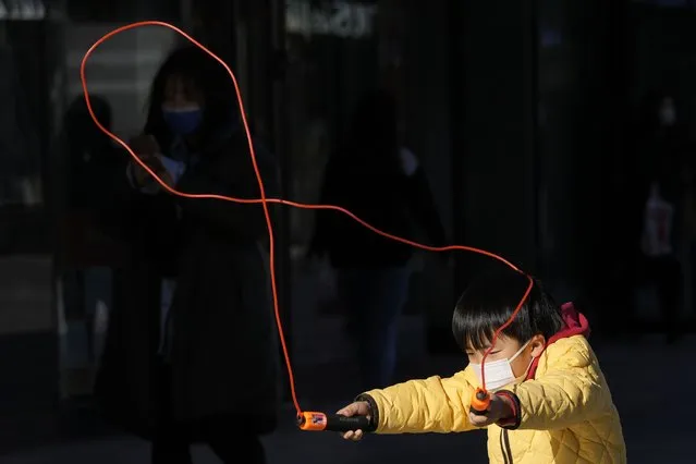 A child wearing a mask plays jump rope in Beijing, China, Thursday, December 30, 2021. (Photo by Ng Han Guan/AP Photo)