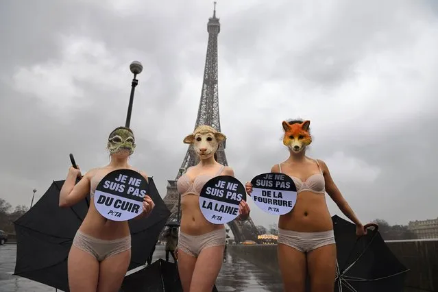 Three women wearing animal masks and holding placards which translates as “I am not leather”, “I am not wool” and “I am not fur” during an action organized by the animal rights organisation People for the Ethical Treatment of Animals (PETA) to protest against the use of animals hides during the Fashion Week, on March 6, 2017 in front of the Eiffel Tower in Paris. (Photo by Eric Feferberg/AFP Photo)