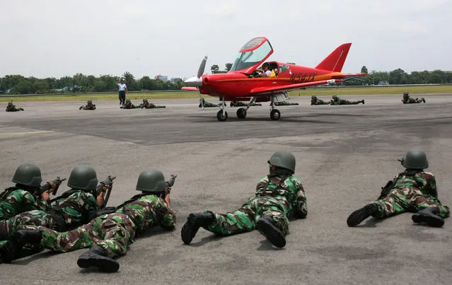 Indonesian soldiers train their weapons at an airplane piloted by 65 year-old Heinz Peier of Switzerland after it was intercepted by Indonesian jet fighters and forced to land at Soewondo Air Base in Medan, North Sumatra, Indonesia, Thursday, April 10, 2014. Peier was on a ferry flight from Colombo to Singapore when he entered Indonesian airspace illegally, an Air Force official said.  (Photo by Binsar Bakkara/AP Photo)