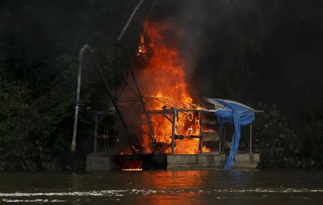 A mining ferry burns down at the banks of Uraricoera River during Brazil’s environmental agency operation against illegal gold mining on indigenous land, in the heart of the Amazon rainforest, in Roraima state, Brazil April 15, 2016. (Photo by Bruno Kelly/Reuters)