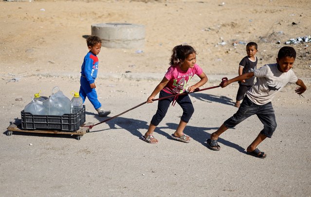 Palestinian children pull water containers as people flee Rafah after Israeli forces launched a ground and air operation in the eastern part of the southern Gaza city, amid the ongoing conflict between Israel and Hamas, in the southern Gaza Strip on May 9, 2024. (Photo by Mohammed Salem/Reuters)