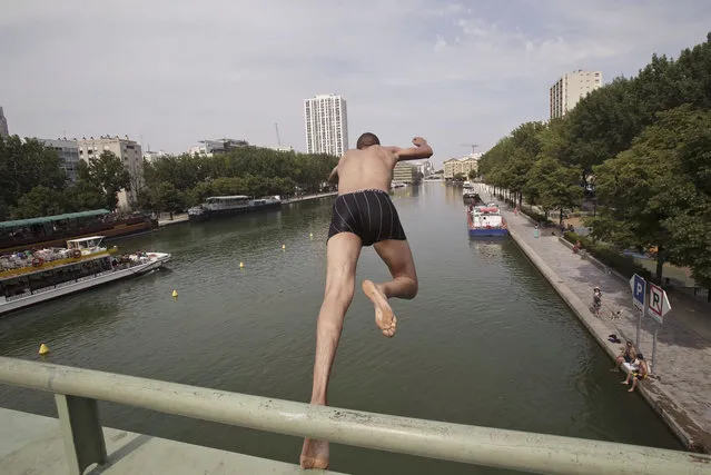 A man jumps from a bridge into the canal of Ourcq in Paris, France, Friday, July 3, 2015. (Photo by Michel Euler/AP Photo)