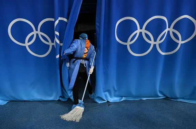 A worker looks behind curtains before the women's play-offs semifinal match of the Beijing 2022 Winter Olympic Games ice hockey competition between USA and Finland, at the Wukesong Sports Centre in Beijing on February 14, 2022. (Photo by Kirill Kudryavtsev/AFP Photo)