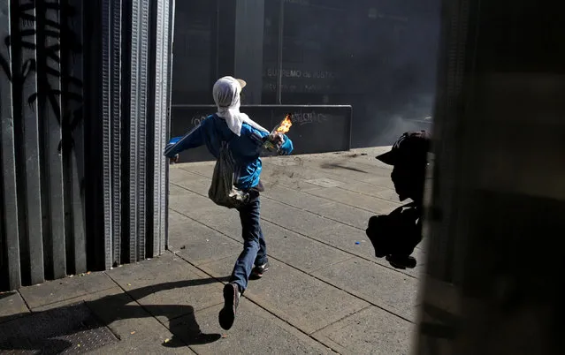 A demonstrator throws a petrol bomb towards an office of the Supreme Court of Justice during a rally in Caracas, Venezuela, April 8, 2017. (Photo by Marco Bello/Reuters)