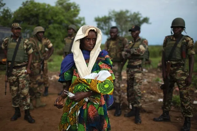 The relative of a woman that recently gave birth yesterday to twins holds one of the babies before departing towards Chad's border, escorted by troops from the African Union operation in CAR (MISCA) in the northern town of Kaga Bandoro April 29, 2014. Of the remaining Muslims that have been sheltered from sectarian violence in the neighbourhood of PK12 in Bangui, over one thousand have been evacuated towards the northern town of Kabo and Sido on the border with Chad. (Photo by Siegfried Modola/Reuters)