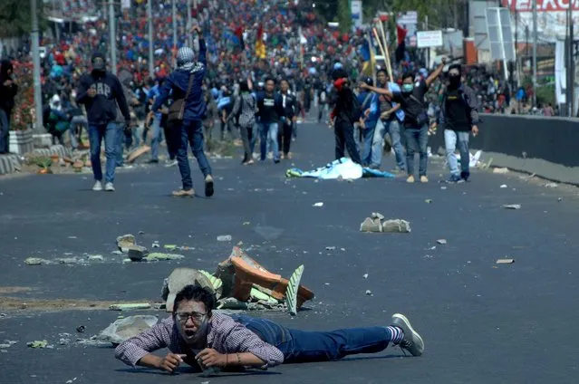 A man lies on the road as protesters clash with police during university students' protest in Makassar, South Sulawesi province, Indonesia on September 24, 2019. (Photo by Abriawan Abhe/Antara Foto via Reuters)