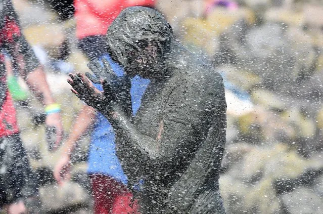 A player gets a shower after her match at the so called "Wattoluempiade" (Mud Olympics) in Brunsbuettel at the North Sea, July 11, 2015. (Photo by Fabian Bimmer/Reuters)