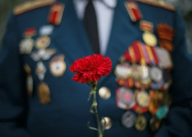 A former Soviet serviceman holds a carnation as he attends a wreath laying ceremony at a World War Two memorial during the celebrations marking Victory Day, in the Black Sea port of Odessa May 9, 2014. Ukraine celebrates the 1945 victory over Nazi Germany during World War Two on May 9. (Photo by Gleb Garanich/Reuters)