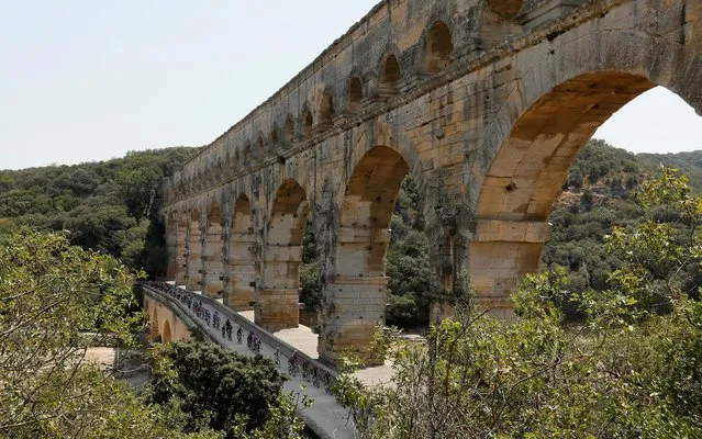 The pack rides next to the Pont du Gard during the sixteenth stage of the Tour de France cycling race over 117 kilometers (73 miles) with start and finish in Nimes, France, Tuesday, July 23, 2019. (Photo by Gonzalo Fuentes/Reuters)