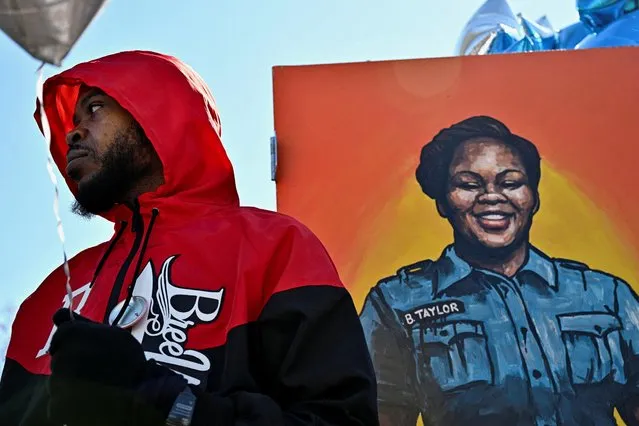 Kenneth Walker III, the boyfriend of Breonna Taylor, stands next to a painting of her at a gathering to mark two years since police officers shot and killed Breonna Taylor when they entered her home, at Jefferson Square Park in Louisville, Kentucky, U.S., March 13, 2022. (Photo by Jon Cherry/Reuters)