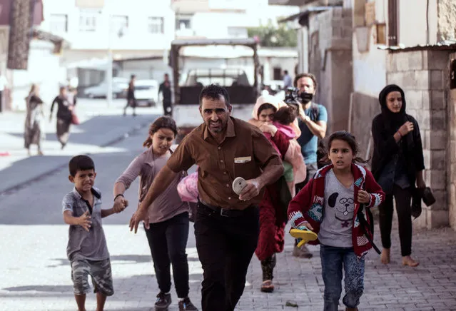 People run to take cover after mortars fired from Syria, in Akcakale, Turkey, Thursday, October 10, 2019. An Associated Press journalist said at least two government buildings were hit by the mortars in Sanliurfa province's border town of Akcakale and at least two people were wounded. (Photo by Ismail Coskun/IHA via AP Photo)