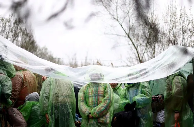 Ukrainian refugees wait in line to cross the Ukraine-Poland border, after fleeing the Russian invasion of Ukraine, outside the border crossing checkpoint in Shehyni, Ukraine, March 31, 2022. (Photo by Hannah McKay/Reuters)