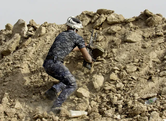 An Iraqi Federal policeman perches on a berm outside Fallujah, 40 miles (65 kilometers) west of Baghdad, Iraq, Tuesday, May 24, 2016. (Photo by Rwa Faisal/AP Photo)